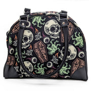 A black purse with a bold pattern featuring skulls, coffins, and eyeballs in orange and green shades.
