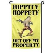 A garden flag with a yellow background featuring a cartoon image of a frog holding a gun and the texts 'HIPPITY HOPPETY' and 'GET OFF MY PROPERTY'.