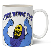A white ceramic mug with an illustration of the character Skeletor from Masters of the Universe with the phrase 'I LIKE BEING EVIL' on it.